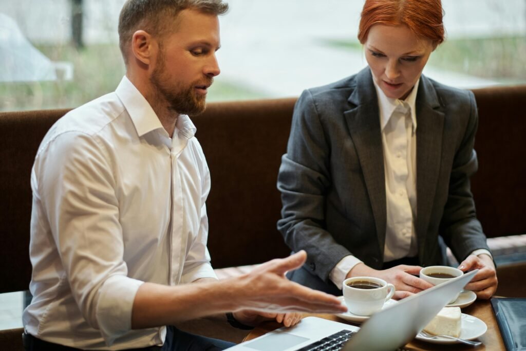 Two business professionals discussing work over coffee in a cafe setting.